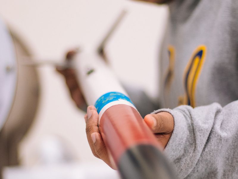 A student examining a model rocket in a STEM lab